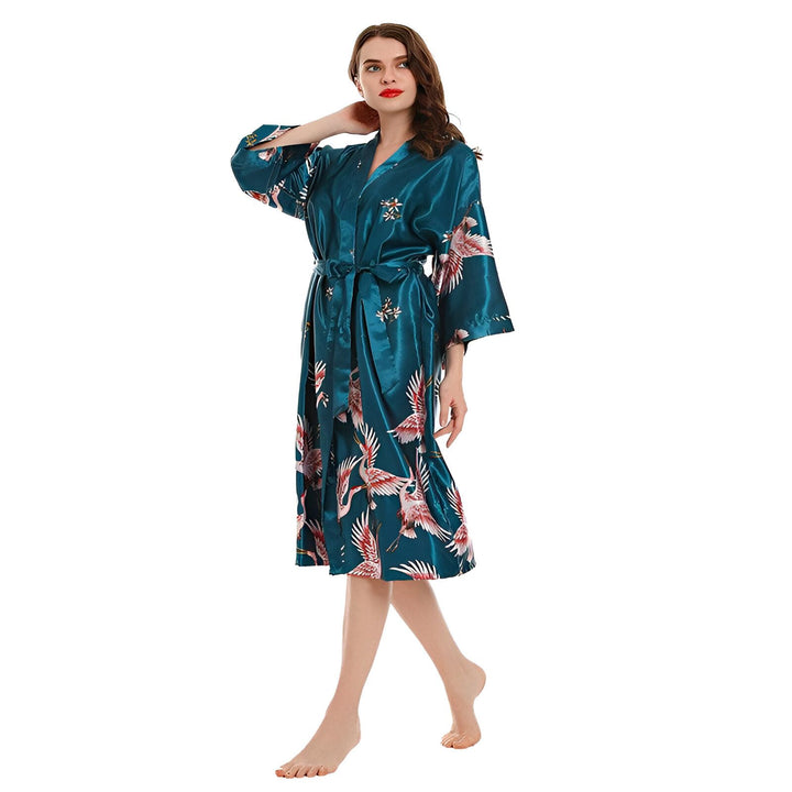 Femme portant un kimono turquoise en soie avec des motifs de grues roses. Vente de kimonos en ligne.