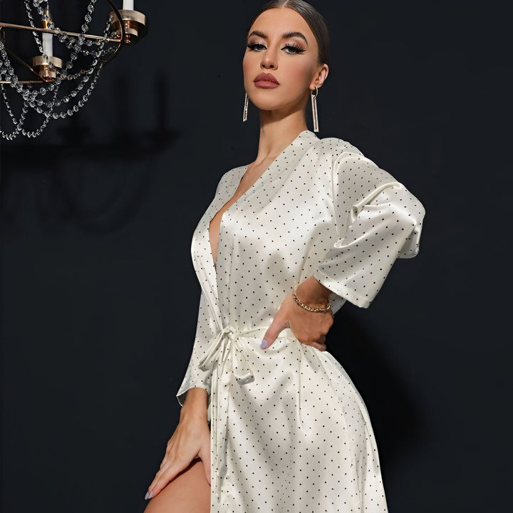 Femme portant un kimono blanc à pois noirs. Kimono élégant avec ceinture, idéal comme vêtement d'intérieur ou de détente. Notre collection de kimonos offre confort et style.