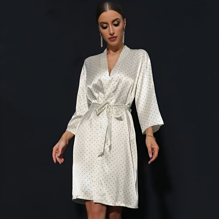 Femme portant un kimono court blanc à pois noirs, ceinturé à la taille. Vente de kimonos pour femmes. Élégance et confort pour la maison.