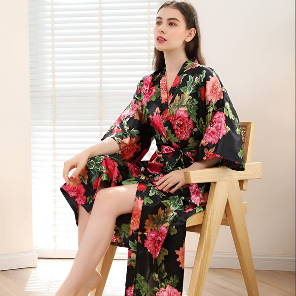 Femme portant un kimono fleuri noir et rose. Vêtements de détente élégants. Découvrez notre collection de kimonos uniques.