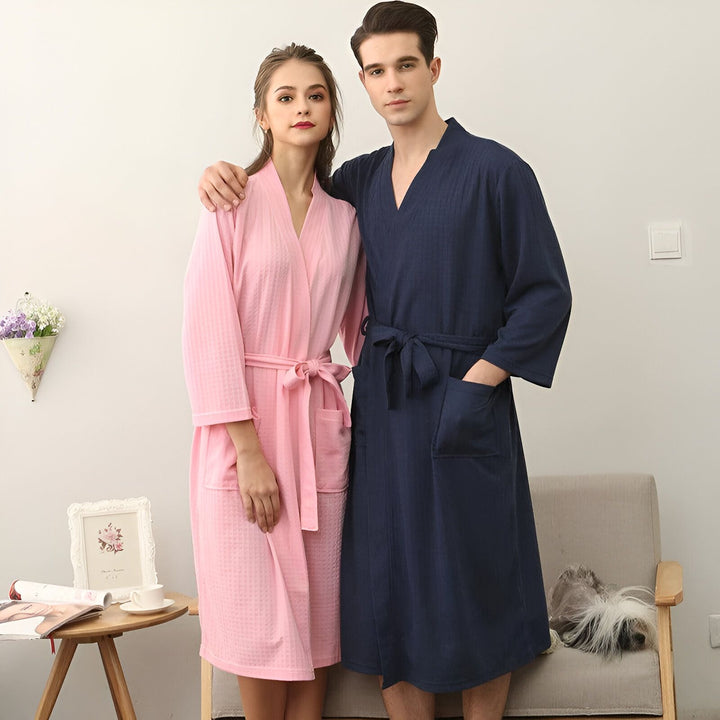 Couple souriant portant des kimonos assortis rose et bleu marine. Vente de kimonos confortables pour hommes et femmes. Kimonos de bain doux et élégants.