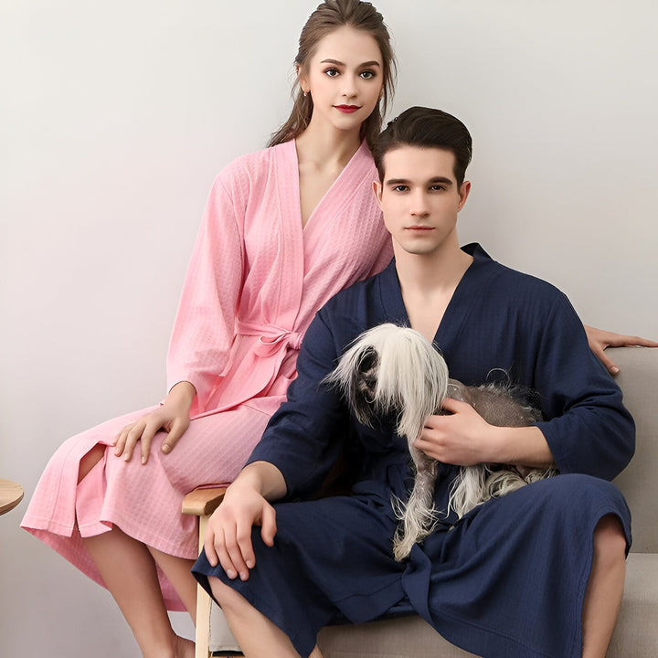 Couple portant des kimonos, femme en kimono rose et homme en kimono bleu marine. Un chien est assis sur les genoux de l'homme. Kimonos confortables à vendre.