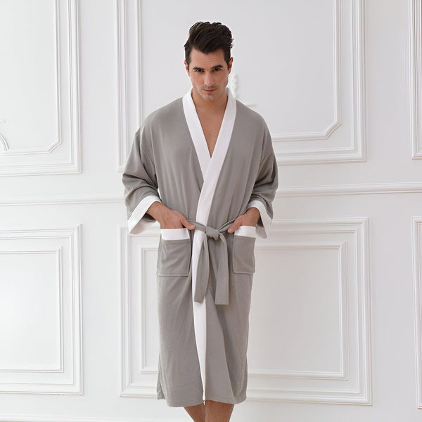 Homme portant un kimono gris avec bordures blanches. Vêtement d'intérieur confortable et élégant, idéal après le bain ou pour se détendre à la maison. Découvrez notre collection de kimonos pour hommes.