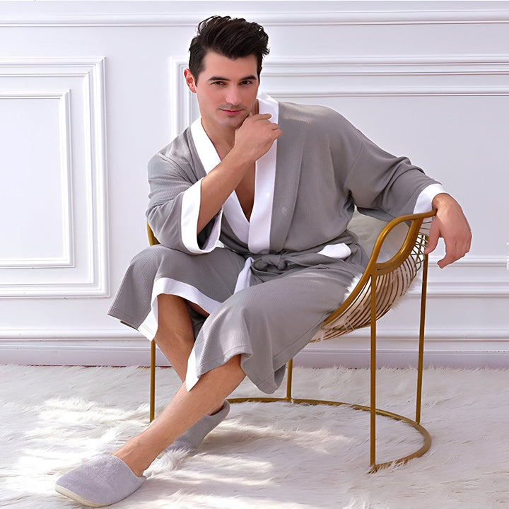 Homme élégant portant un kimono gris et blanc, assis sur une chaise dorée. Vente de kimonos pour hommes et femmes.