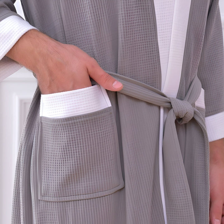 Détail d'un kimono/peignoir en coton gris avec bordures blanches, poche et ceinture nouée. Confort et élégance pour votre intérieur. Découvrez notre collection de kimonos.