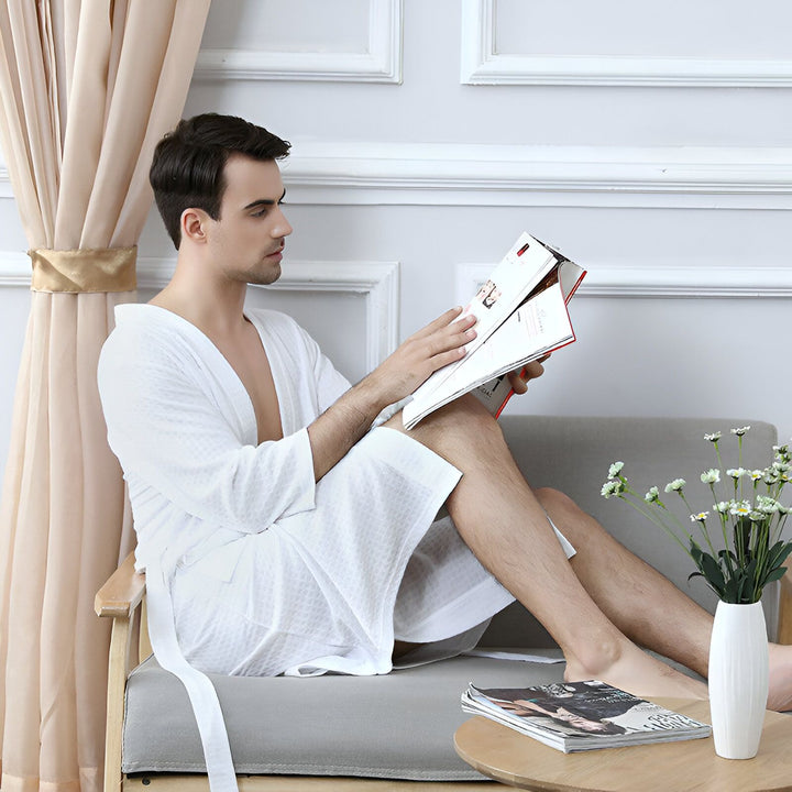 Homme élégant en kimono blanc, lisant un magazine. Vente de kimonos confortables pour hommes et femmes. Détente à la maison.