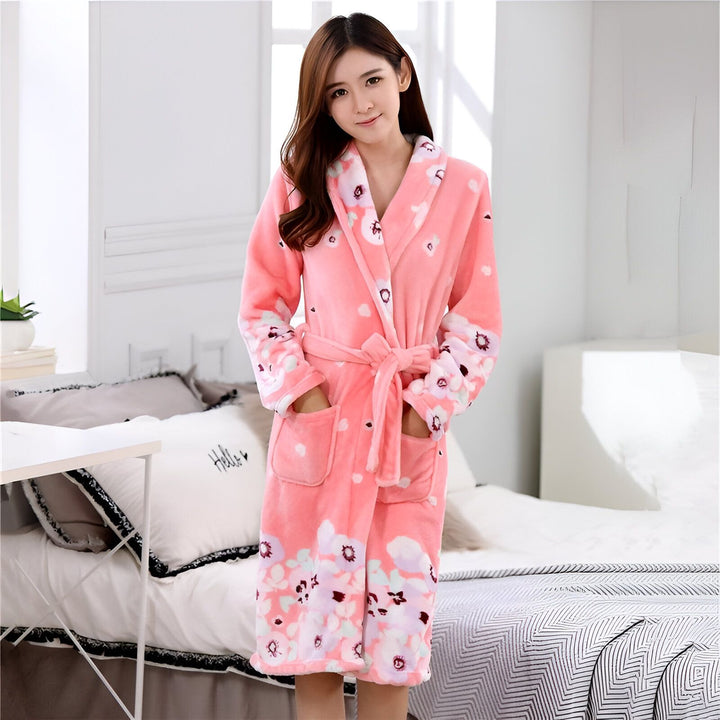 Femme portant un kimono rose à motifs floraux, avec ceinture, poches, manches longues. Fond de chambre à coucher. Kimono confortable et élégant.