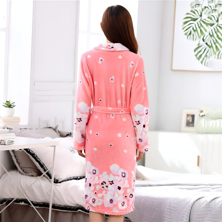 Femme portant un kimono rose à motifs floraux, vue de dos. Peignoir confortable et élégant, parfait pour la détente. Découvrez notre collection de kimonos.