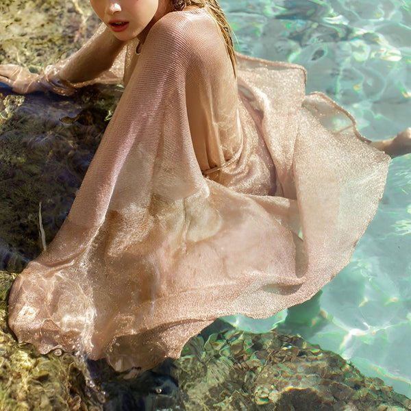 Femme portant un kimono doré dans l'eau turquoise. Élégance et style pour vos moments de détente. Découvrez notre collection de kimonos uniques.