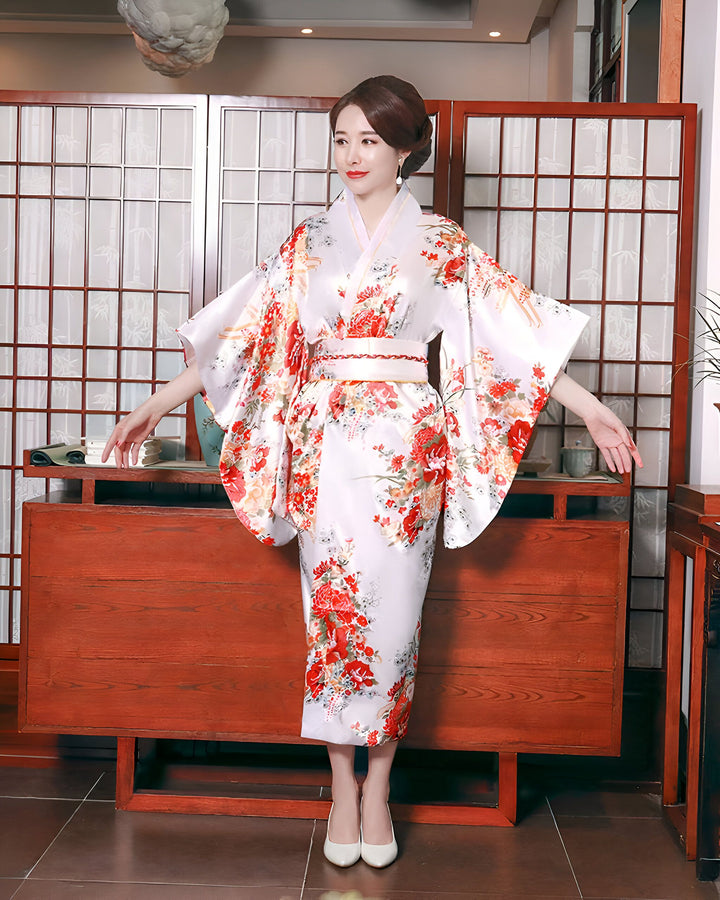 Femme portant un kimono blanc à motifs floraux rouges. Élégance et tradition japonaises. Découvrez notre collection de kimonos uniques.