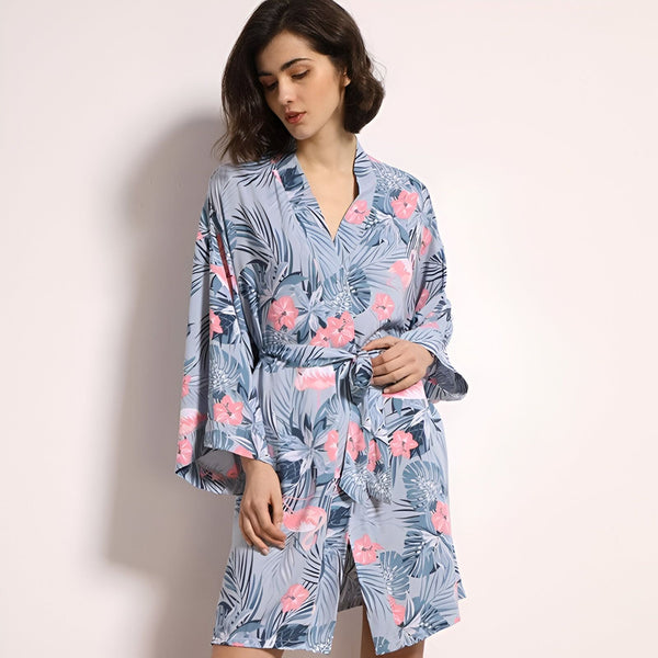 Femme portant un kimono court à motifs floraux bleus et roses. Vêtement d'intérieur confortable et élégant. Parfait pour la détente. Découvrez notre collection de kimonos.