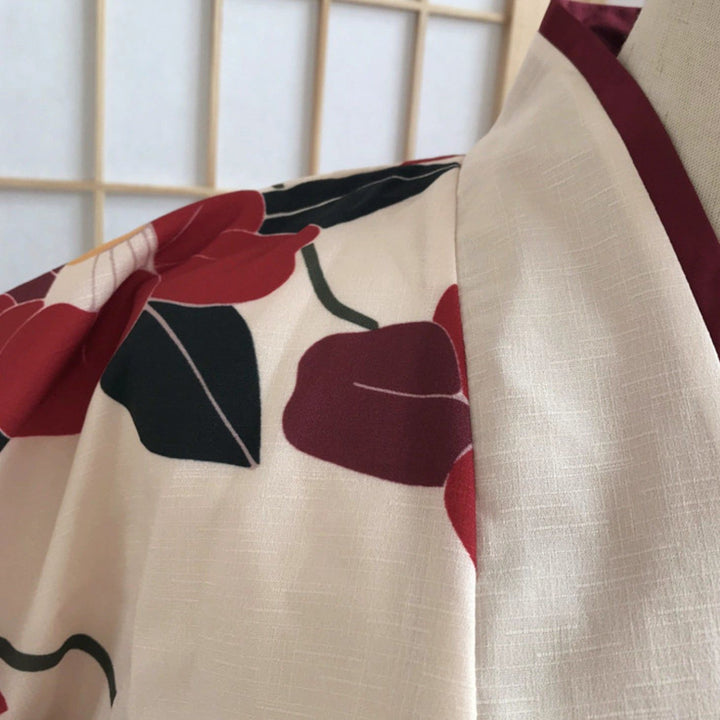 Détail d'un kimono avec motif floral rouge et noir sur fond beige. Finition bordeaux. Kimonos traditionnels japonais en vente.