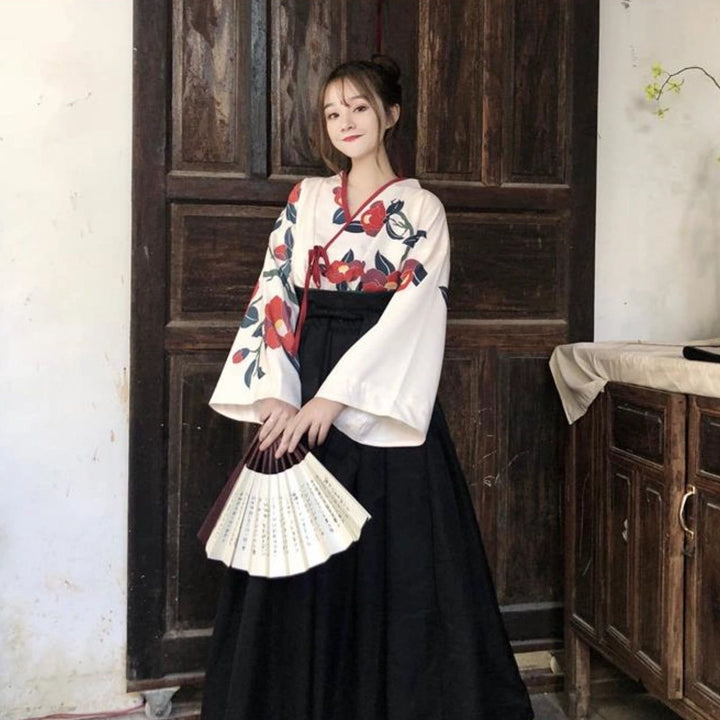 Femme en kimono fleuri blanc et noir, tenant un éventail. Vêtements japonais traditionnels à motifs floraux. Découvrez notre collection de kimonos uniques.