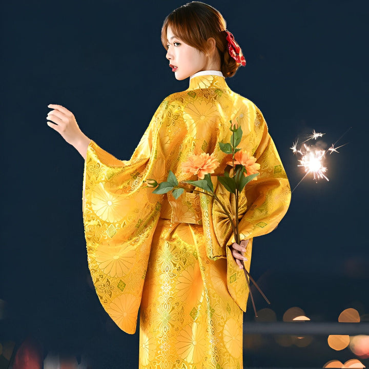Femme portant un kimono jaune traditionnel avec des motifs floraux, tenant des fleurs et un feu d'artifice. Vente de kimonos de haute qualité.