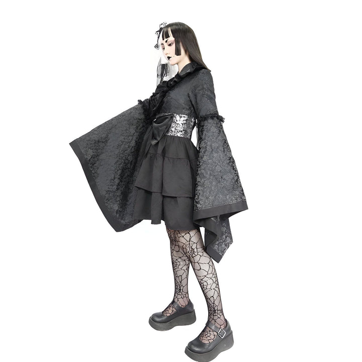 Femme portant un kimono gothique noir avec des motifs floraux, une ceinture argentée, des collants résille et des chaussures plateformes. Kimono style japonais pour un look unique.