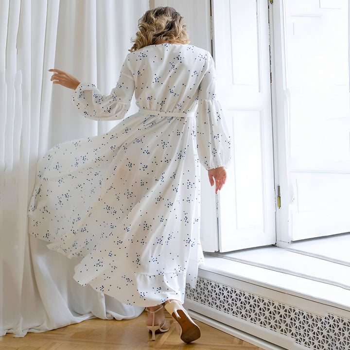 Femme vue de dos portant un kimono long blanc à motifs bleus. Kimono avec manches amples et ceinture. Idéal pour la vente de kimonos en ligne.