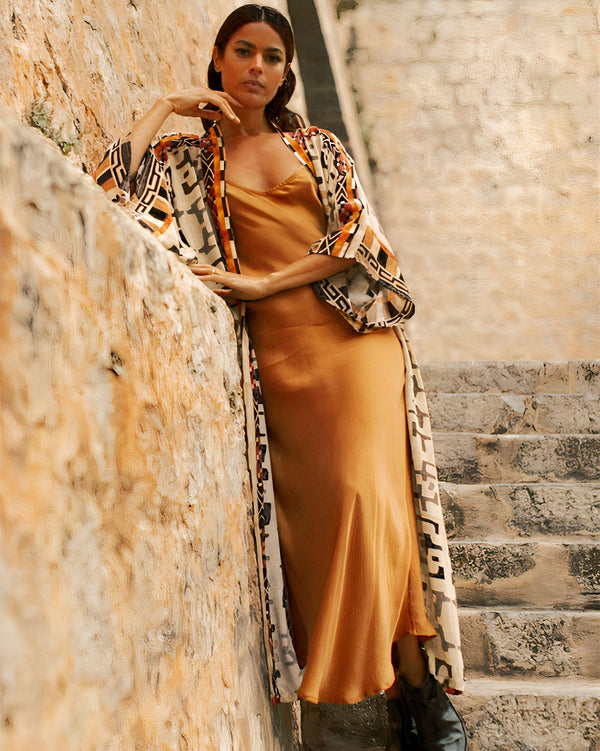 Femme portant un kimono imprimé avec une robe couleur rouille. Kimono de notre collection, idéal pour toutes les occasions. Découvrez notre gamme de kimonos élégants et confortables.