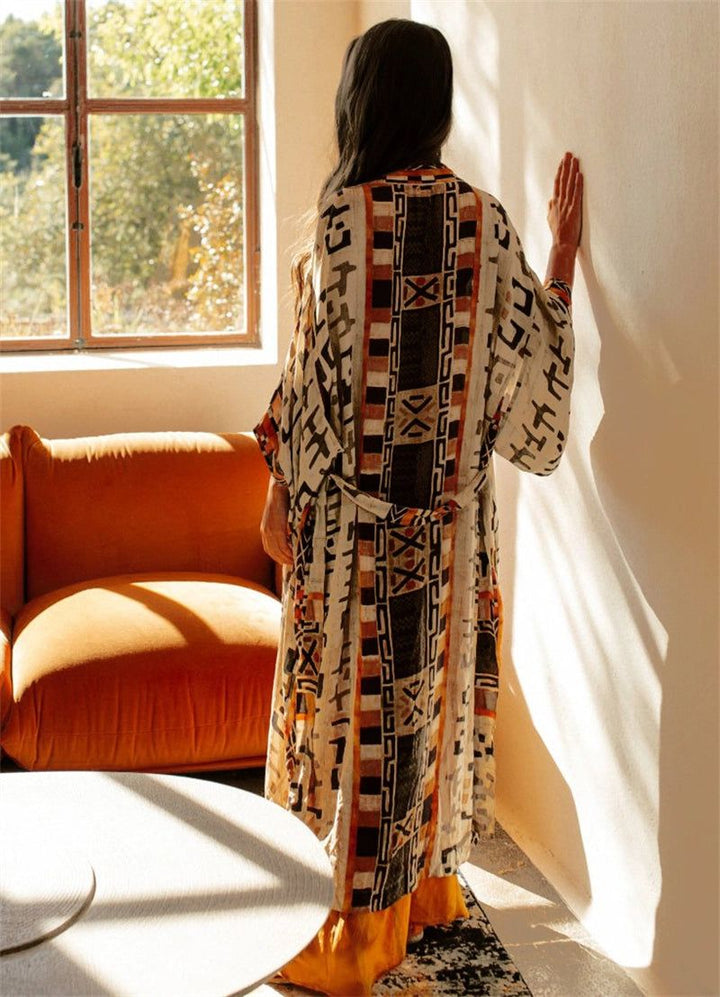Femme portant un kimono à motifs ethniques dans une pièce ensoleillée. Collection de kimonos uniques.
