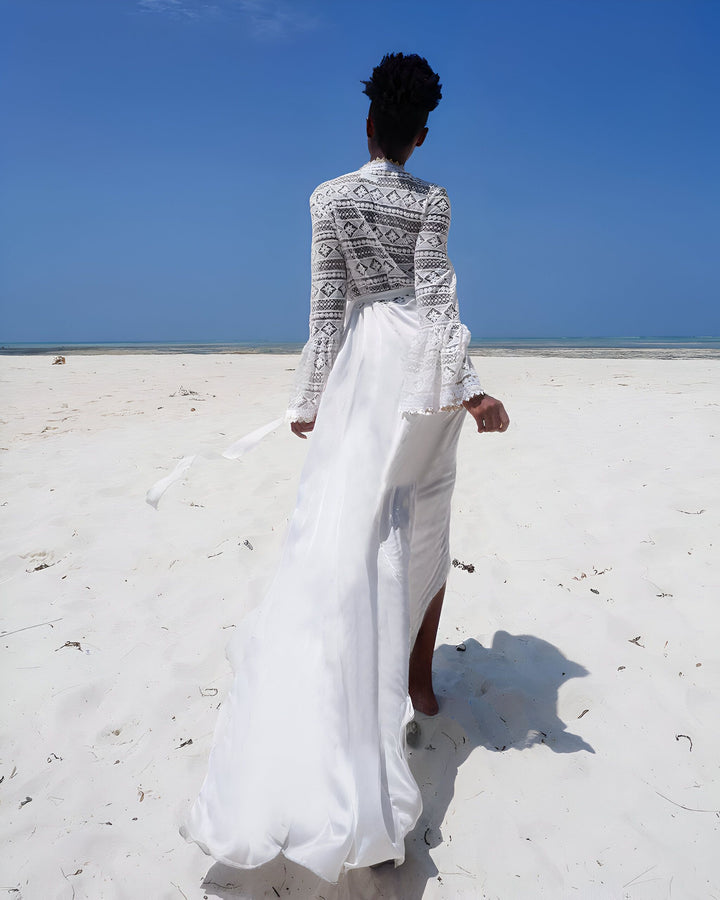 Femme vue de dos portant un kimono blanc en dentelle sur une plage de sable blanc. Vêtements de plage élégants. Collection de kimonos.