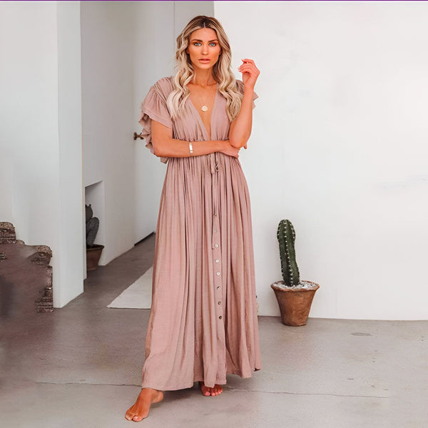 Femme blonde portant une longue robe style kimono couleur pêche avec col en V et boutons. Détails à volants aux manches. Parfait pour un look décontracté et élégant.