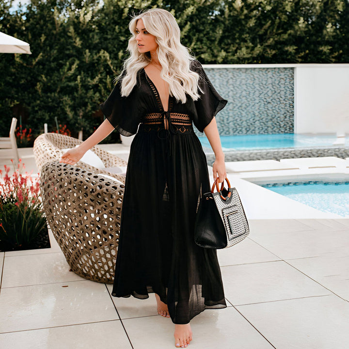 Femme blonde portant un kimono noir élégant près de la piscine. Notre collection de kimonos offre un style chic et confortable. Trouvez le kimono parfait pour votre prochaine escapade estivale.