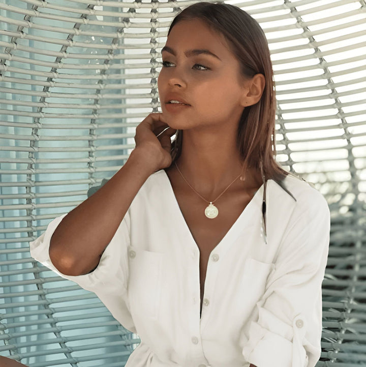 Femme portant un kimono blanc léger dans un fauteuil. Découvrez notre collection de kimonos pour un look décontracté et élégant.