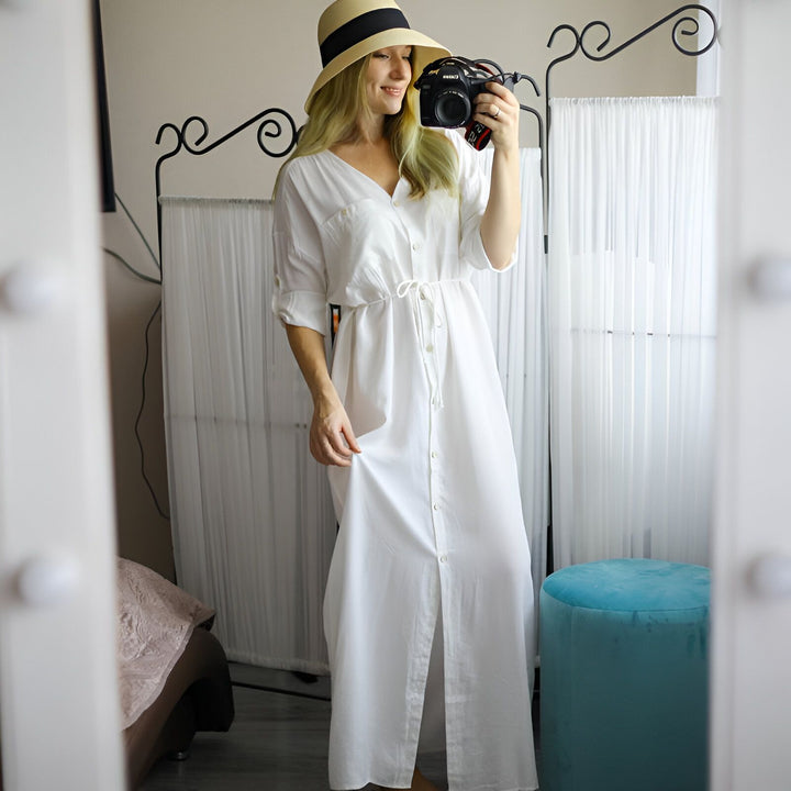 Femme prenant un selfie dans un miroir, portant une robe kimono blanche et un chapeau de paille. Idée de tenue décontractée et élégante. Boutique de kimonos en ligne.