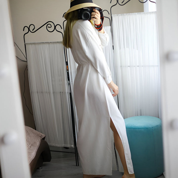 Femme portant un kimono blanc long avec fente, chapeau de paille et appareil photo. Style décontracté, vêtements amples. Idéal pour la maison, la plage ou comme peignoir. Collection de kimonos.