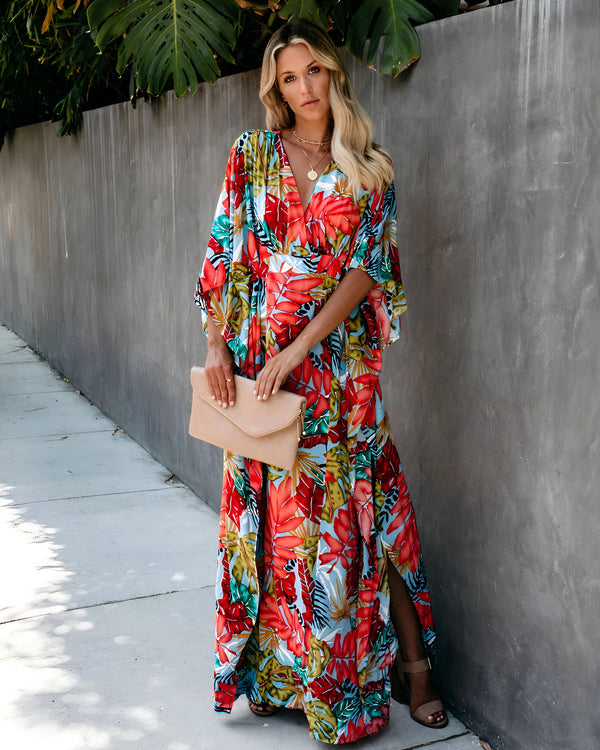 Femme blonde portant un kimono long et coloré à motifs floraux. Elle tient une pochette beige. Vêtements de style kimono.