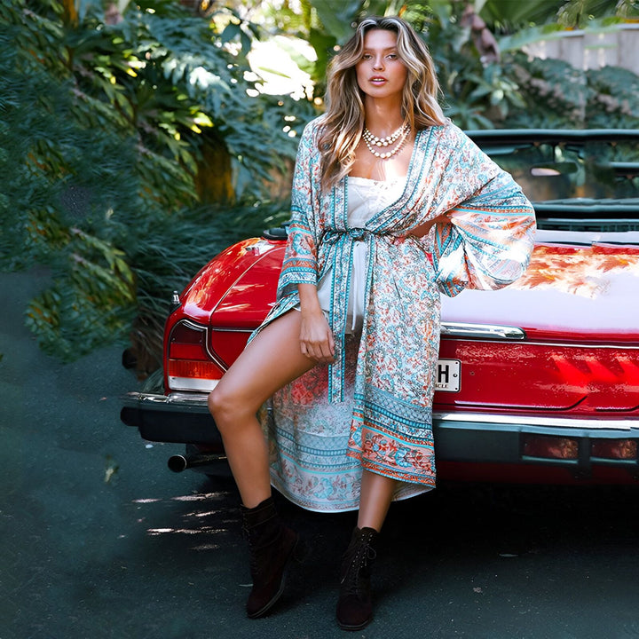 Femme portant un kimono à motifs devant une voiture rouge vintage. Kimono bohème chic à vendre, parfait pour un look estival élégant et décontracté.