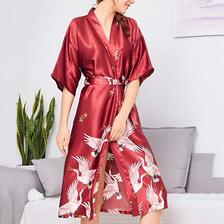 Femme portant un kimono bordeaux à motifs de grues blanches. Vêtement de détente élégant et confortable. Idéal pour la maison ou comme cadeau.