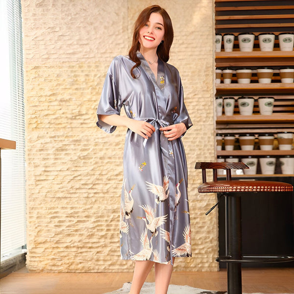 Femme souriante portant un kimono gris avec des motifs de grues. Vêtements de détente élégants et confortables. Kimonos de haute qualité disponibles à l'achat.