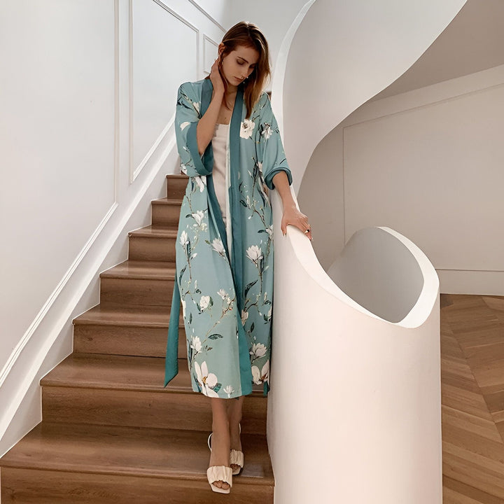 Femme descendant un escalier en kimono turquoise à motifs floraux. Vente de kimonos en ligne. Élégance et confort pour la maison.
