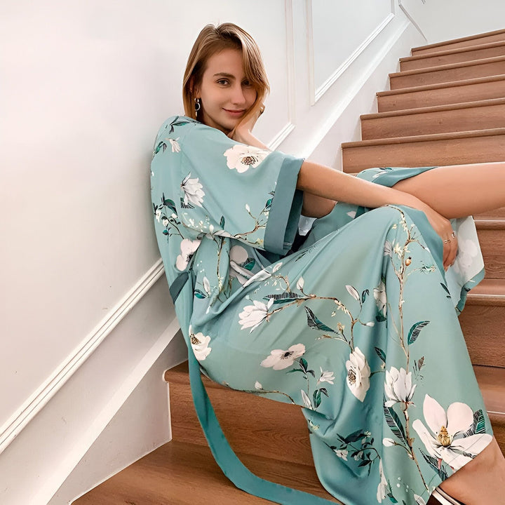 Femme portant un kimono à motifs floraux turquoise, assise sur un escalier. Vente de kimonos en ligne.