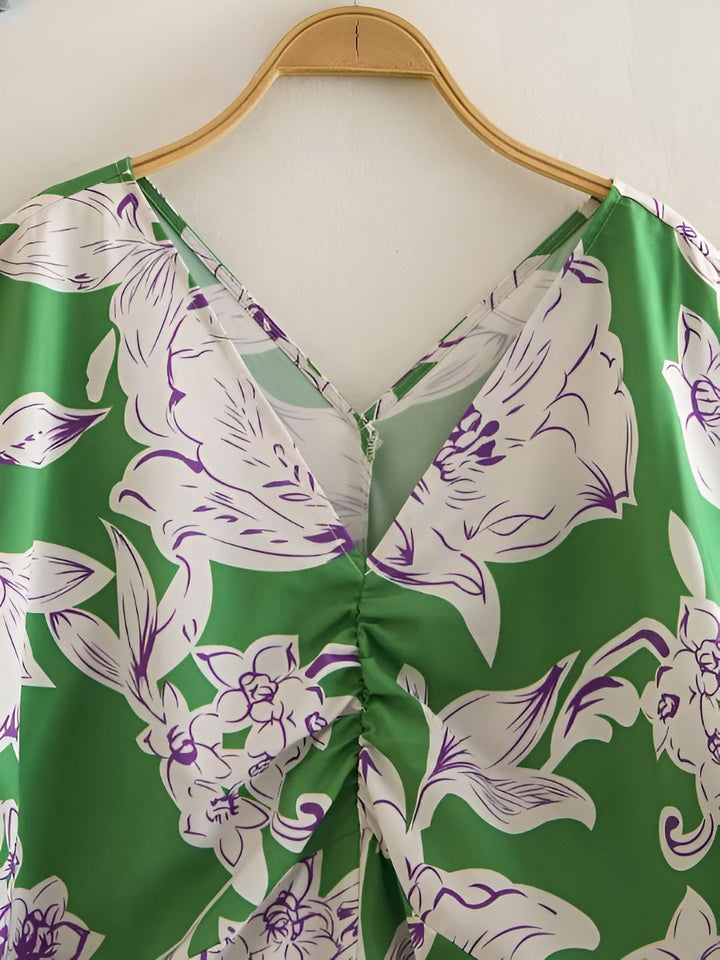 Détail d'un kimono vert à motifs floraux blancs et violets. Encolure en V et fronces au niveau de la poitrine. Vêtement de style japonais, parfait pour un look élégant et décontracté.