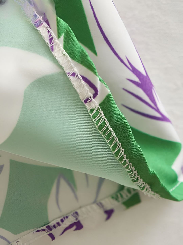 Détail du tissu d'un kimono. Motifs de feuilles vertes et violettes sur fond blanc. Couture de qualité visible. Kimono original, texture et finitions soignées.