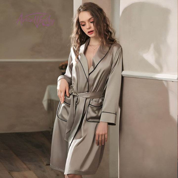 Femme portant un kimono gris en soie avec ceinture. Vêtement d'intérieur élégant avec bordure noire, parfait pour se détendre avec style. Découvrez notre collection de kimonos de luxe.