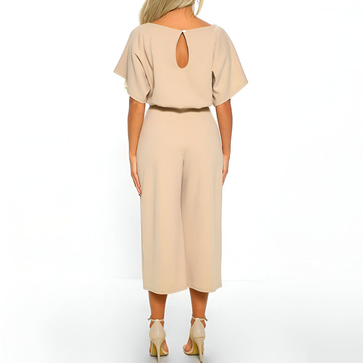 Dos d'une femme portant une combinaison beige rappelant un kimono, avec des manches courtes amples et une ouverture en forme de goutte dans le dos, complétée par des talons hauts. Vente de kimonos en ligne.