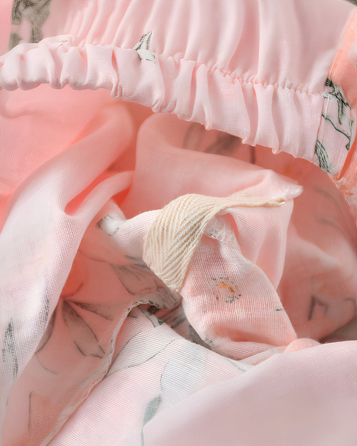 Détail d'un kimono rose pâle à motifs floraux, avec un cordon de serrage et des volants délicats. Texture douce et légère, idéale pour un style japonais élégant et confortable. Découvrez notre collection de kimonos uniques.
