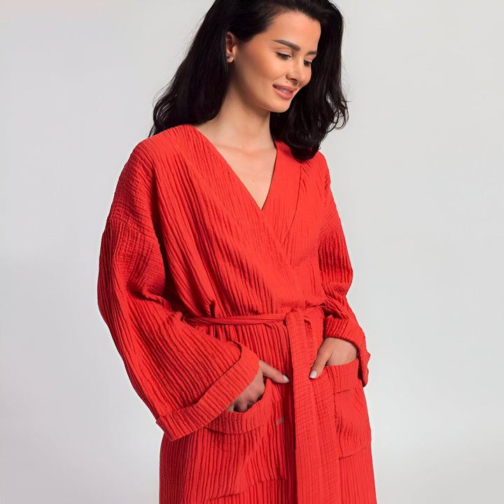 Femme portant un kimono rouge texturé avec ceinture. Vente de kimonos de haute qualité. Idéal pour la détente à la maison ou comme vêtement de nuit élégant. Découvrez notre collection de kimonos uniques et confortables.
