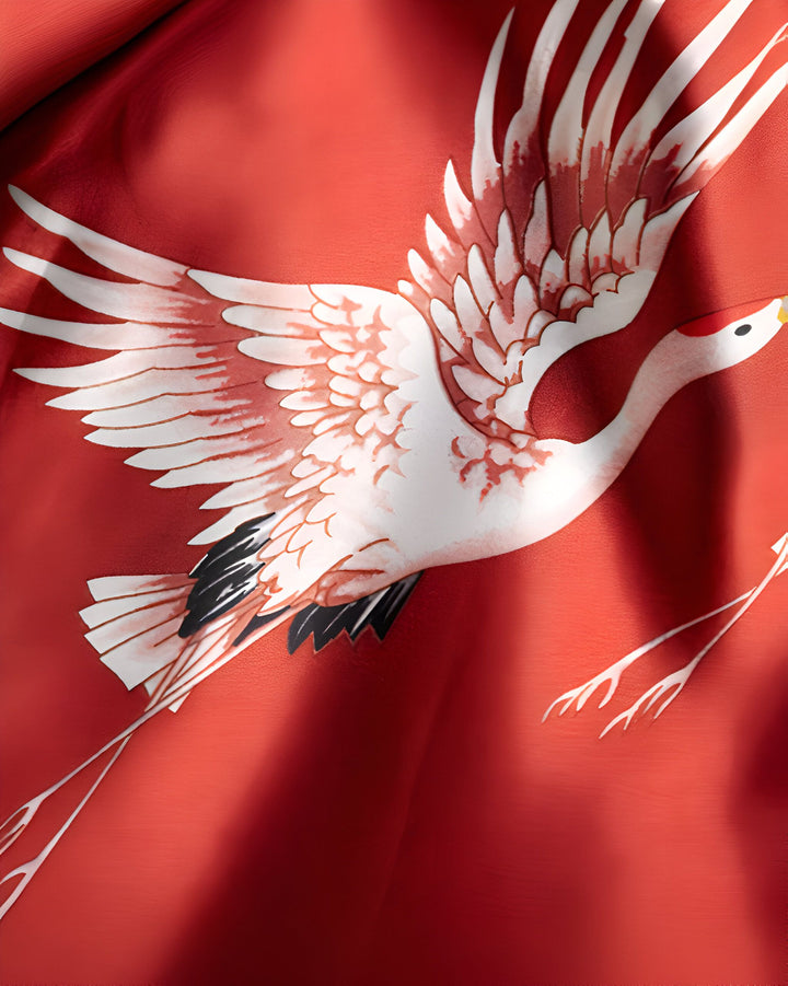 Gros plan d'un kimono rouge avec un motif de grue blanche en vol. Tissu de qualité supérieure pour un vêtement traditionnel japonais élégant. Découvrez nos kimonos uniques.