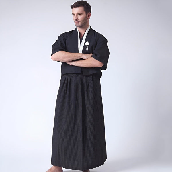 Homme portant un kimono noir traditionnel japonais avec un col blanc et une jupe hakama noire à rayures. Vêtements japonais pour hommes, vente de kimonos en ligne.