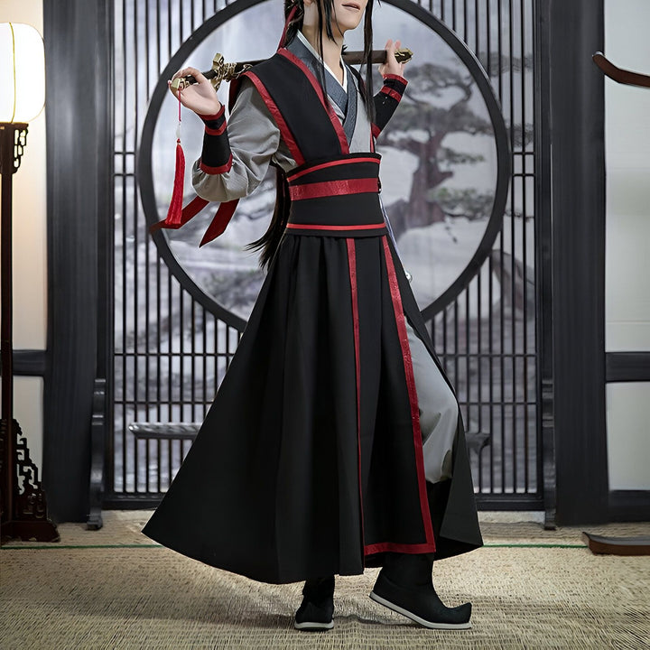 Un homme en costume traditionnel asiatique noir et rouge, tenant une épée. Il est devant une porte ronde avec un motif d'arbre. Le costume a une ceinture rouge et des garnitures rouges.