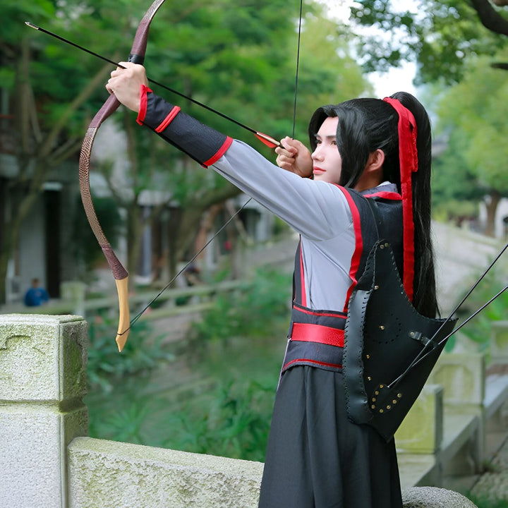 Un jeune homme en costume traditionnel chinois tire à l'arc dans un jardin. Il porte un carquois en cuir noir et a les cheveux longs attachés avec un ruban rouge. Son arc est en bois et il vise avec concentration.