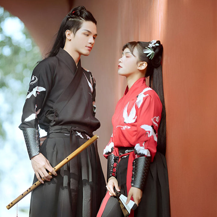 Couple portant des kimonos traditionnels avec des motifs de grues, l'homme tenant une flûte. Vêtements japonais élégants disponibles à l'achat.