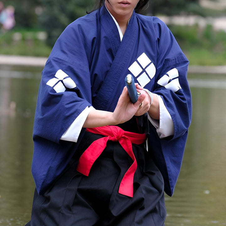 Homme en kimono bleu traditionnel avec motifs blancs, tenant un katana. Vêtements japonais authentiques disponibles à l'achat.