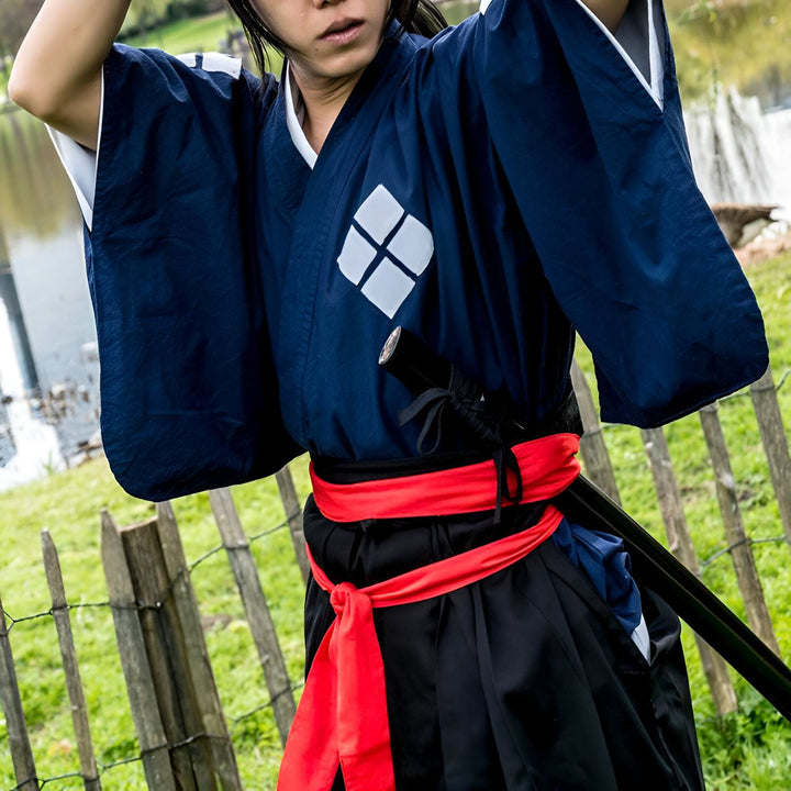 Homme portant un kimono traditionnel bleu marine avec motif losange blanc, ceinture rouge et katana. Vente de kimonos authentiques.