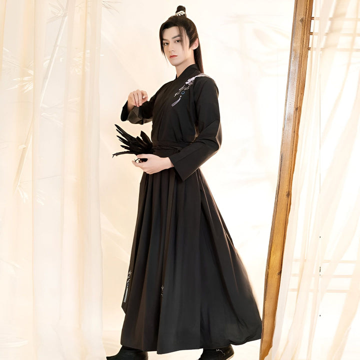 Homme portant un kimono noir traditionnel avec des broderies, tenant un éventail. Vêtements japonais classiques à vendre.