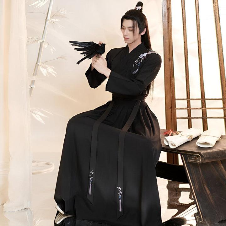 Homme portant un kimono noir traditionnel avec un oiseau noir à la main. Vêtements de style asiatique. Kimonos de haute qualité disponibles à l'achat.