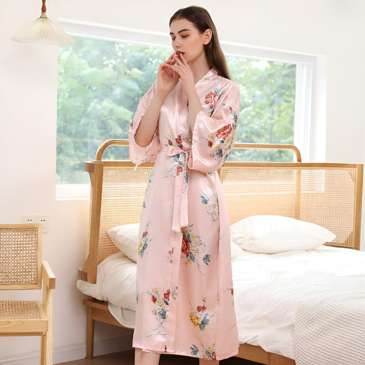 Femme portant un kimono rose à motifs floraux. Vente de kimonos en ligne. Peignoir fleuri doux et confortable. Kimono de luxe pour femmes. Boutique de kimonos.